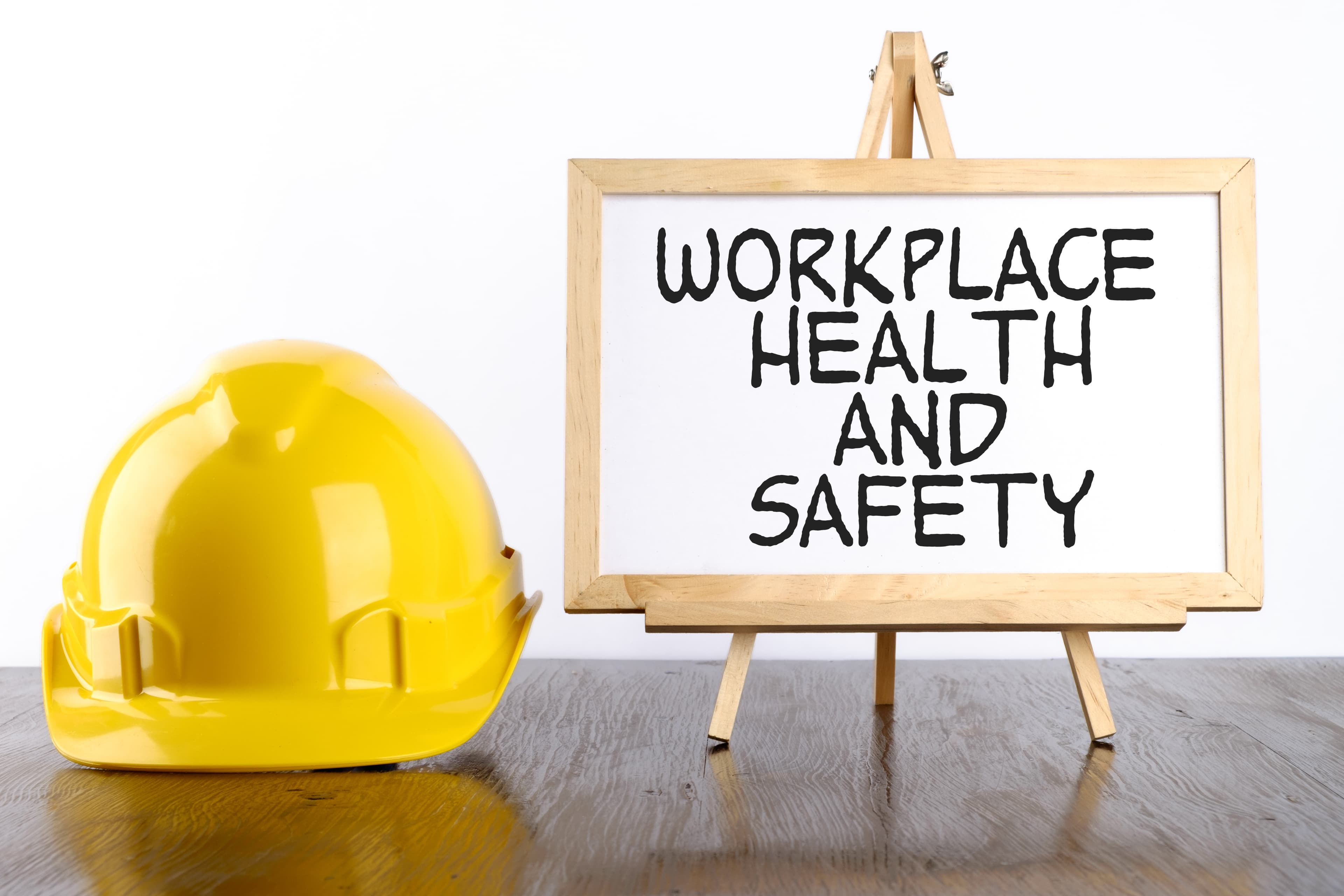 Safety helmet and warning signs representing management commitment to workplace safety